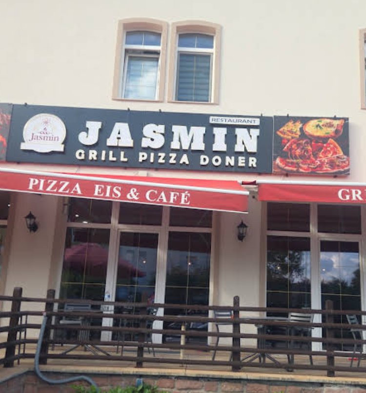 Außenansicht von Jasmin Restaurant mit Schild, Markise und Terrasse
